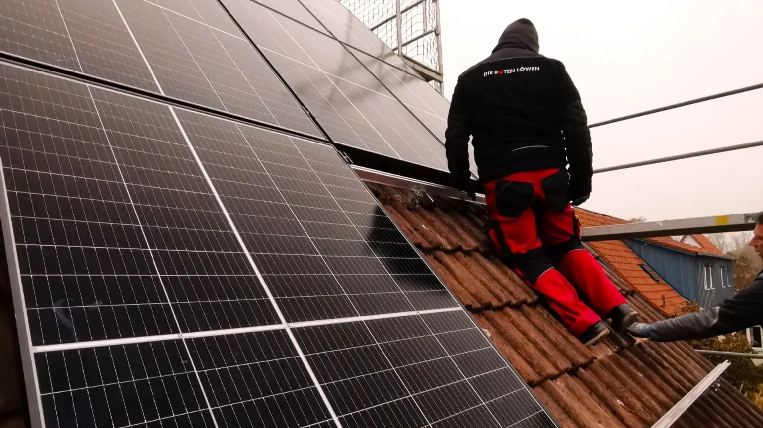 Handwerker montiert Solarmodule auf einem Ziegeldach bei der Photovoltaik-Installation